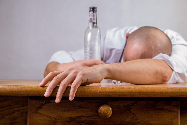 二日酔いで頭を抱え、後悔している男性